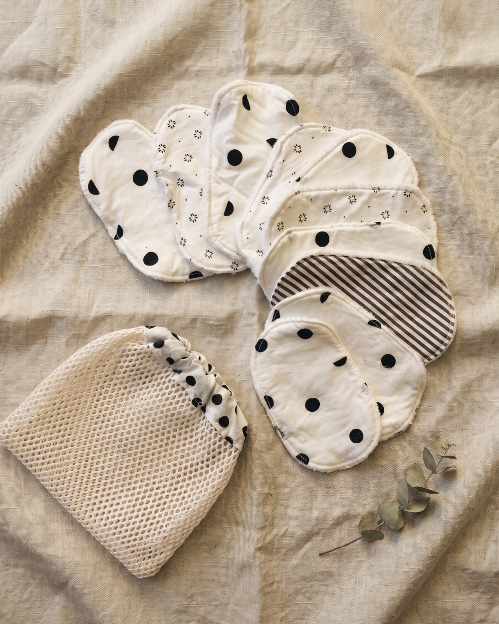 Lingettes lavables en éventail sur du lin écru, avec leur filet de lavage